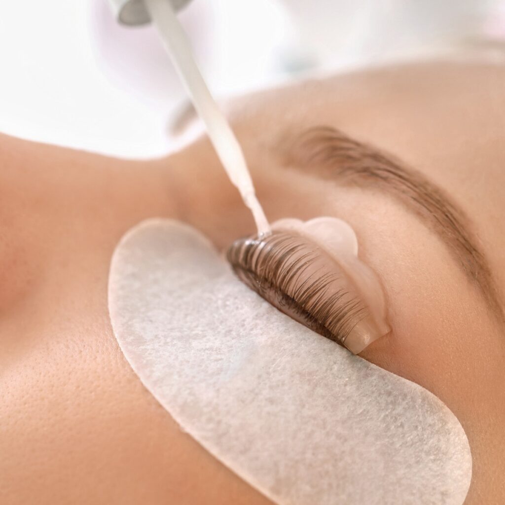 Young woman undergoing procedure of eyelashes lamination in beauty salon closeup jpg