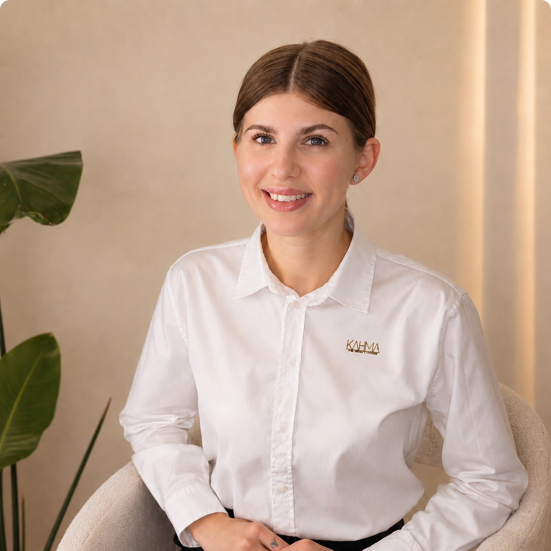 Laechelnde Frau mit braunem Scheitelhaar in weisser Bluse mit Logo